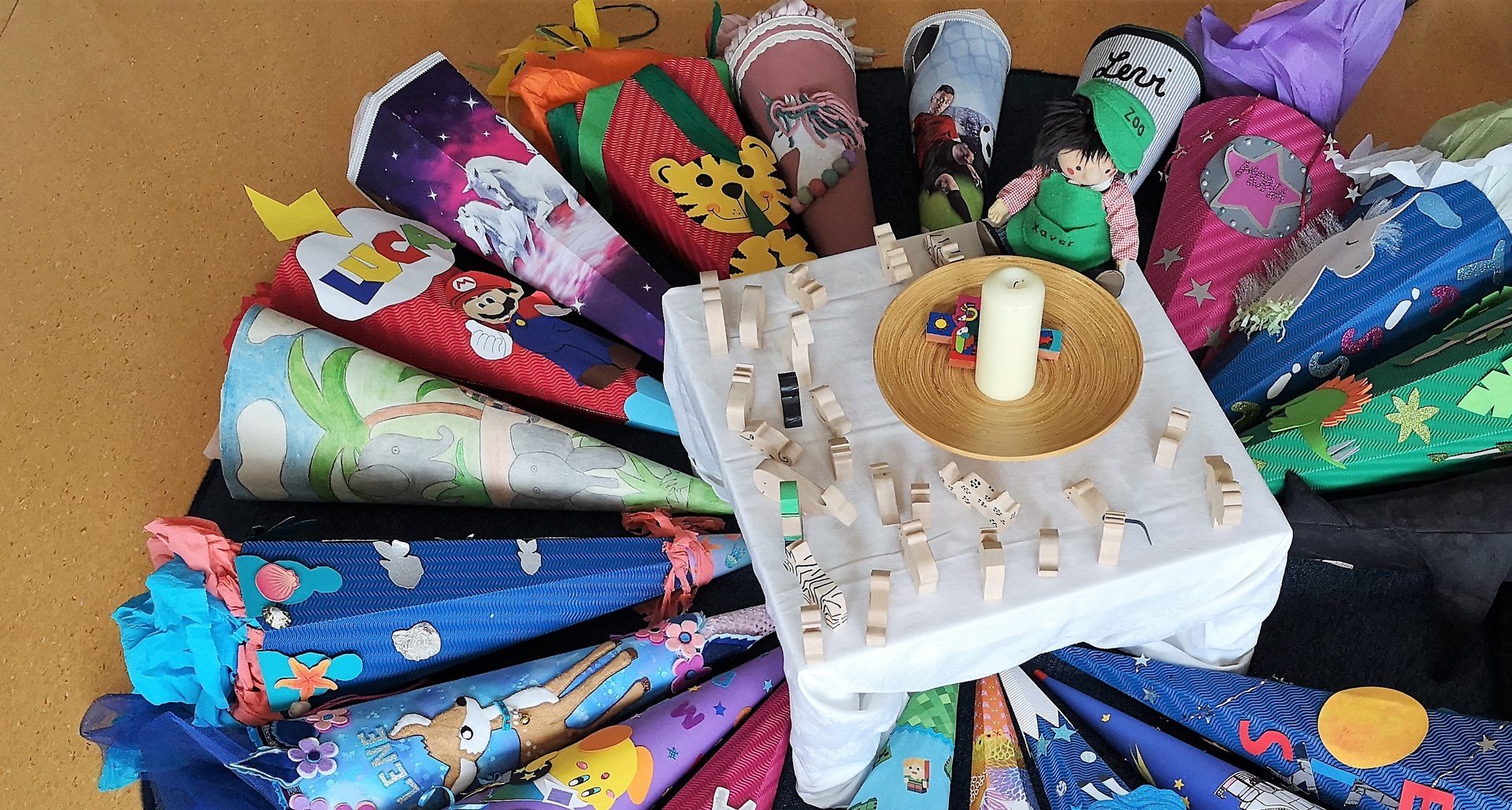 Bunte Schultüten im Kreis um Kerze und Holzkreuze zur Einschulung an der St.-Michael-Grundschule