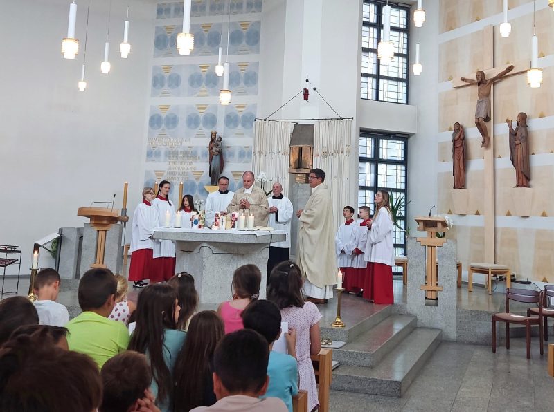 Schulgottesdienst mit Kindern, Ministranten und Priestern am Altar der Pfarrkirche St. Albert
