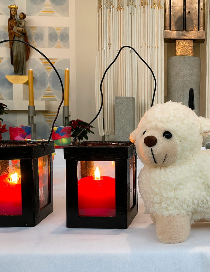 Stofflamm und Laternen mit roten Kerzen vor dem Altar, religiöses Leben an der St.-Michael-Grundschule