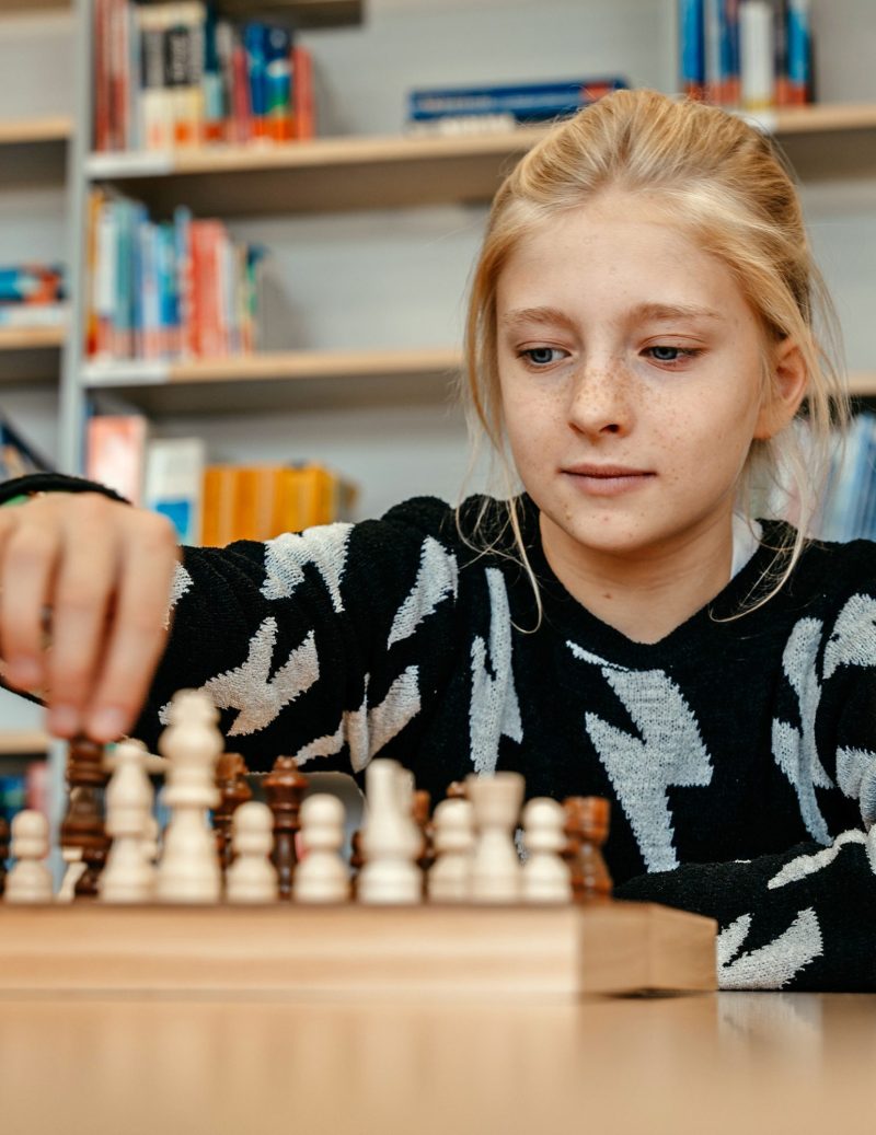 Schülerin zieht eine Figur am Schachbrett in der Schulbibliothek, St.-Michael-Grundschule Neu-Ulm